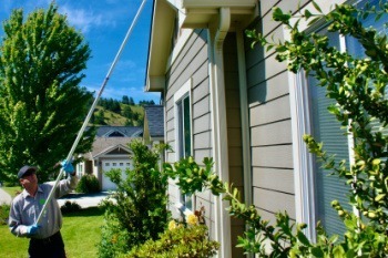 Pest Technician Cleaning Spider Webs from Eaves